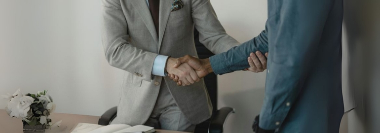 A close-up of a fresh graduate shaking hands professionally with a hiring manager.