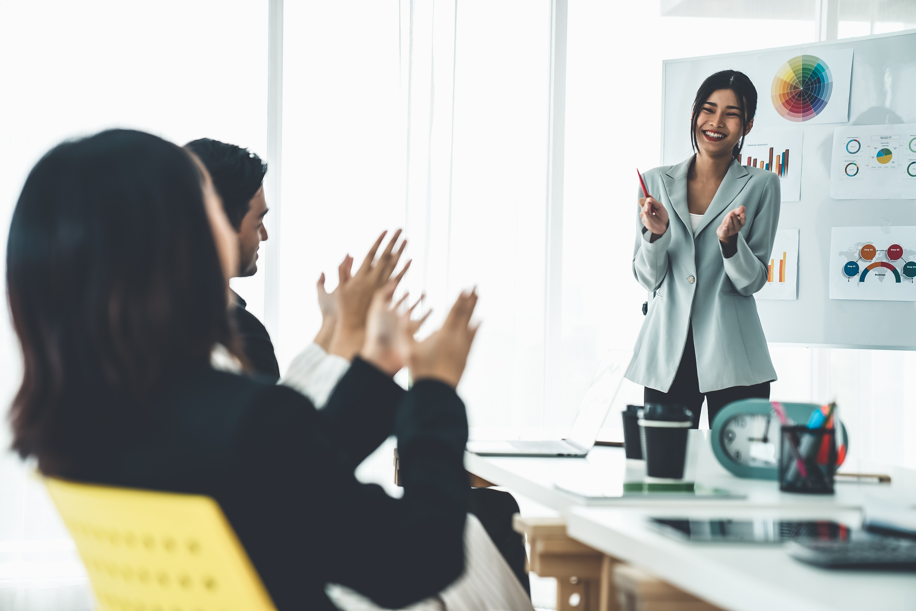 A woman enthusiastically claps her hands during a meeting, showing support and engagement with the discussion.