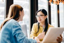 Two women engaged in conversation while seated at a table