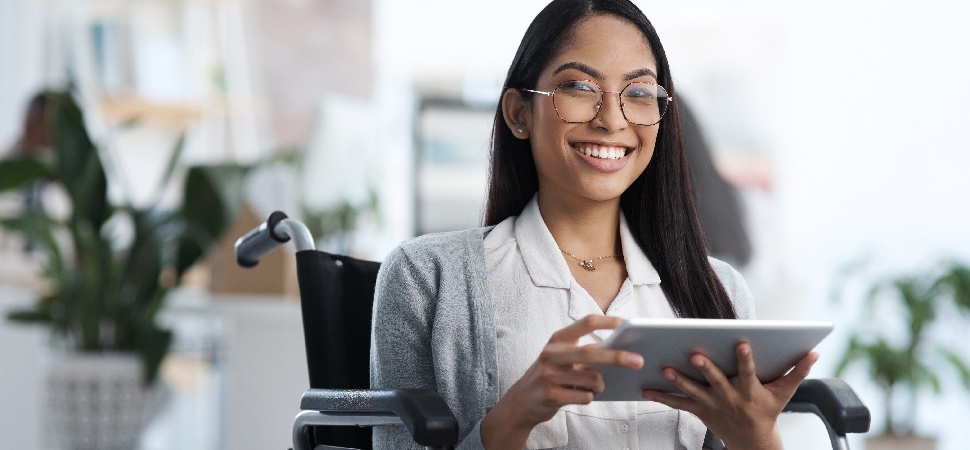 Woman in a wheelchair holding a tablet in an office
