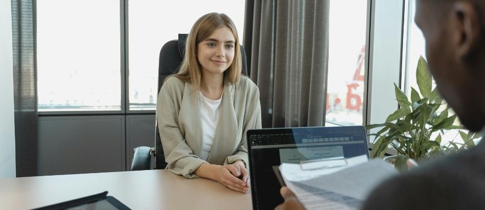 A female candidate sitting across interviewer while smiling confidently