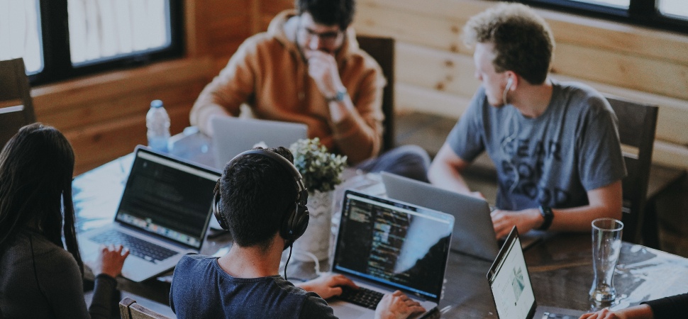 four people discussing in front of laptop