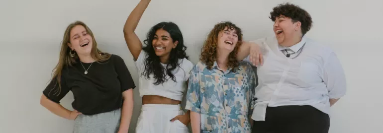 Four people standing together, laughing and smiling.