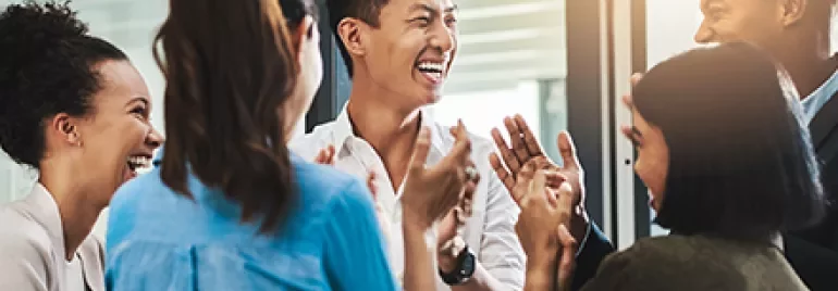 A diverse group of people laughing and clapping together.