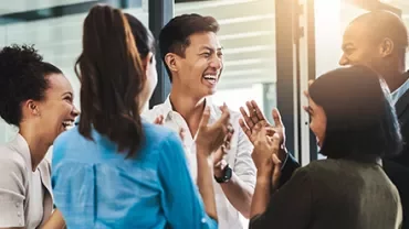 A diverse group of people laughing and clapping together.