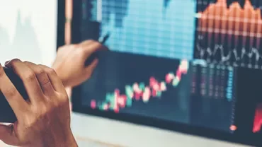 Person analyzing financial charts on a computer screen, talking on the phone.