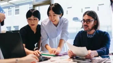 Group of people collaborating at a table in a modern office.