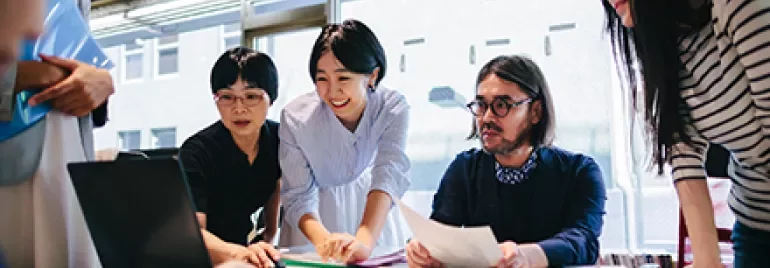 Group of professionals collaborating around a table filled with documents.