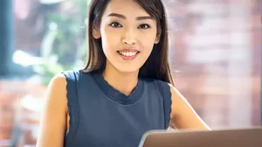 Woman smiling while working on laptop at home office.