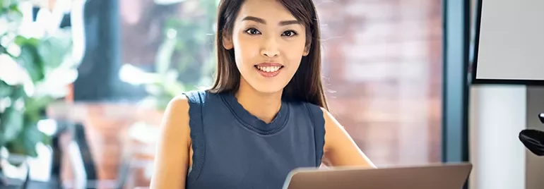 Woman smiling while working on laptop at home office.