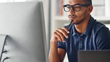 Man wearing glasses working on his computer.