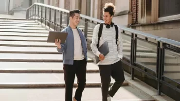Two fresh graduates walking down the stairs while discussing job interview questions