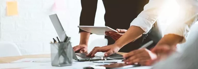 People working together at a desk with laptops and tablets.