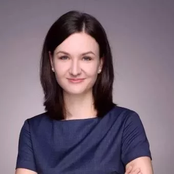 Portrait of a smiling woman with dark hair in a blue shirt.