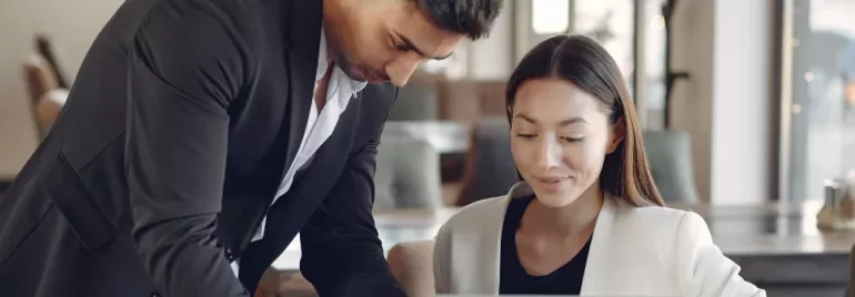 Two colleagues collaborating on a laptop in a modern office.