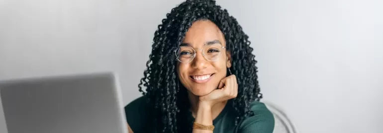 Woman with glasses smiling at a laptop