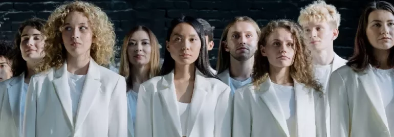 A group of people in white suits standing against a dark background.