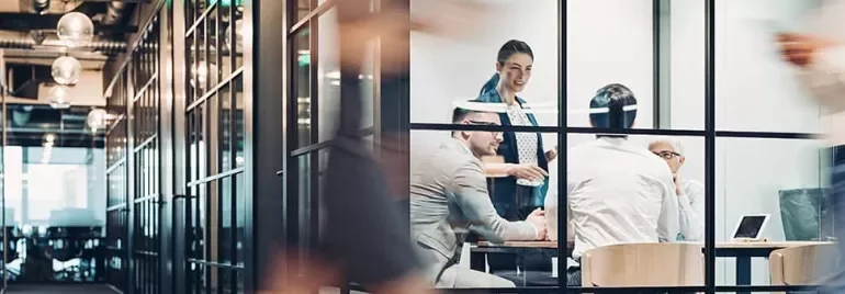 People in a glass-walled office having a meeting.