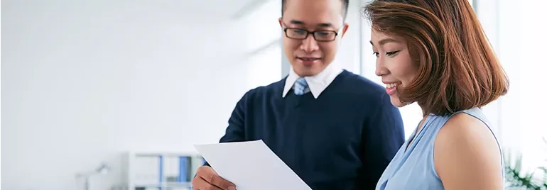 Two people reviewing a document together in a bright office.