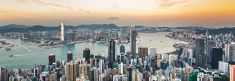 Skyline of a bustling city with skyscrapers and a vibrant harbor at sunset.