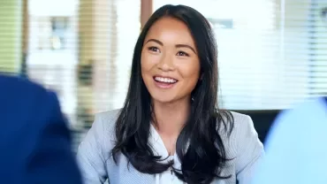 Smiling woman in an office setting, engaged in conversation.