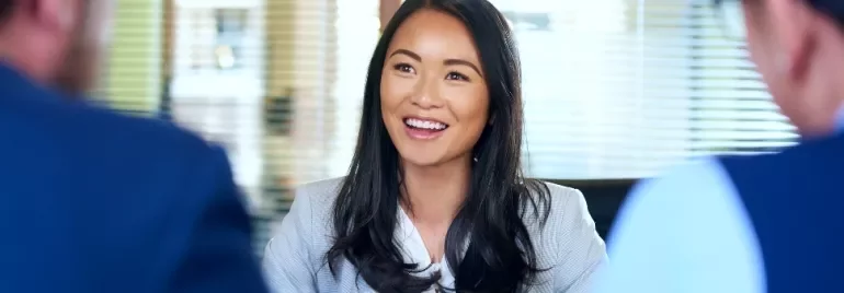 Smiling woman in an office setting, engaged in conversation.