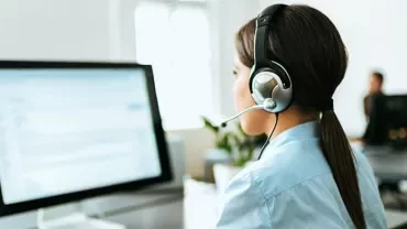 Woman with headset working at a computer in an office.