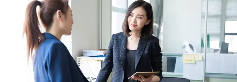 Two women in a discussion in a bright office setting.