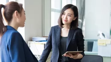 Two women in a discussion in a bright office setting.