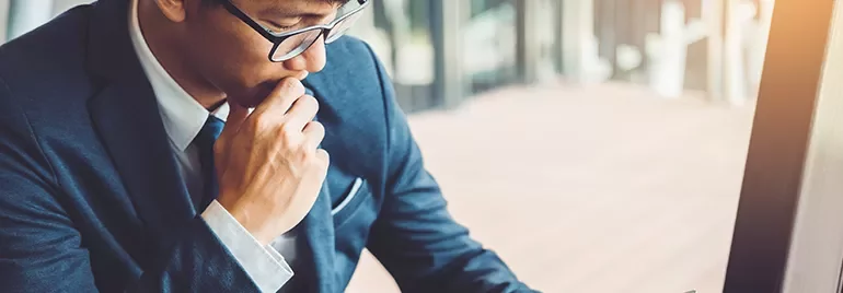 Man in business suit thoughtfully working at a desk.