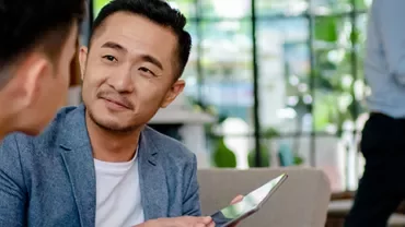 Two men having a conversation in a modern office with greenery.